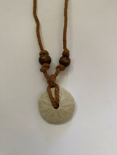 Handmade sand dollar necklace crafted with brown hemp cord and gemstone beads. Casual Brown Necklaces For The Beach, Casual Brown Necklace For Beach, Brown Beach Jewelry With Sliding Knot, Brown Sliding Knot Jewelry For Beach, Brown Beaded Jewelry For Vacation, Adjustable Earthy Necklaces With Waxed Cord, Casual Brown Necklace With Adjustable Cord, Casual Brown Beaded Necklace For The Beach, Casual Brown Beaded Necklace For Beach