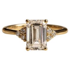 an emerald and diamond ring with three diamonds on the band, set in yellow gold