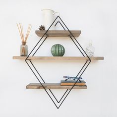 two wooden shelves with books, vases and other items on them against a white wall