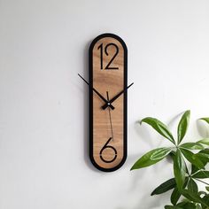 a wooden clock on the wall next to a potted plant