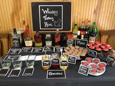 a table topped with desserts and bottles of alcohol next to a chalkboard sign