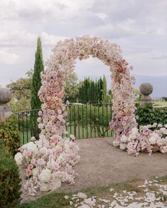 an outdoor wedding ceremony with flowers and greenery on the ground in front of a gate