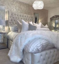 a bed with white fur and pillows in a bedroom