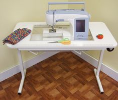 a sewing machine sitting on top of a white table next to a bag and scissors