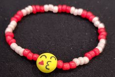 Adorable red and pink seed bead bracelet featuring a kiss emoji bead Novelty Pink Jewelry With Round Beads, Valentine's Day Playful Beaded Jewelry, Casual Round Beads Bracelets For Valentine's Day, Playful Round Beads Jewelry For Valentine's Day, Playful Valentine's Day Jewelry With Round Beads, Casual Beaded Jewelry For Valentine's Day, Cute Red Beaded Bracelets With Heart Beads, Cute Red Beaded Bracelet With Heart Beads, Red Letter Beads For Friendship