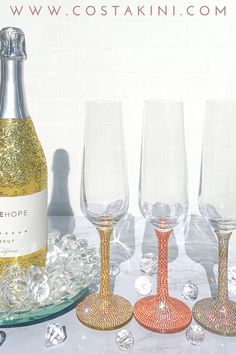 three wine glasses and one champagne bottle on a table