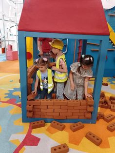 three children playing in a play house made out of bricks