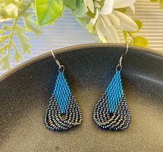 a pair of blue beaded earrings sitting on top of a black plate