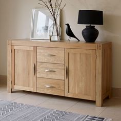 a wooden sideboard with two birds on top and a black lamp next to it