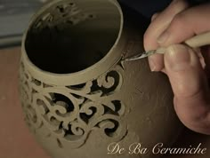 a person is working on a vase with a pen in their left hand and writing on it