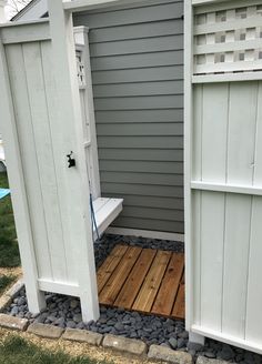 a white bench sitting in the middle of a yard next to a shed and fence