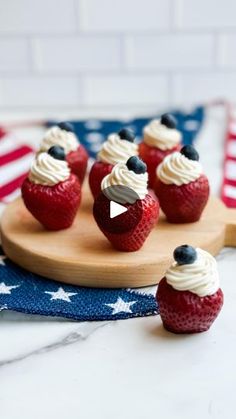 red, white and blue cupcakes on a wooden board with an american flag in the background