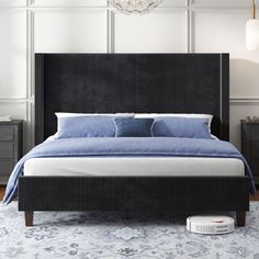 a bed with blue sheets and pillows in a white room next to two nightstands