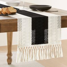 a black and white table runner with tassels on it, sitting on a dining room table