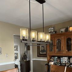 a dining room table and chairs with lights hanging from the ceiling