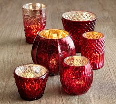 several red glass vases sitting on top of a wooden table