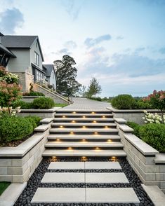 a set of steps leading up to a house with lights on each step and landscaping around them