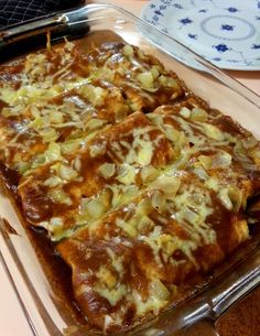 a casserole dish with onions and cheese in it on a table next to a plate