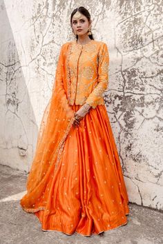 Orange jacket with all over marori floral embroidery and gota embellishments. Comes with can can attached lehenga and dupatta.
Components: 3
Pattern: Embroidered
Type Of Work: Thread, Gota, Marori
Neckline: Scalloped
Sleeve Type: Full
Fabric: Lehenga and Jacket: Pure Spun Silk, Dupatta: Pure Organza
Color: Orange
Other Details: 
Attached lining
Approx. Product Weight: 2.50kg
Closure: Jacket: Front Hook
Model Height: 5 ft 7 inches, wearing size S
Occasion: Sangeet,Reception - Aza Fashions V Neck Lehenga, Jacket Lehenga, Orange Lehenga, Lehenga Pattern, Yellow Lehenga, Wedding Lehenga Designs, Lehenga Designs Simple, Blue Lehenga, Orange Jacket