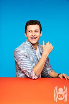 a man sitting at a table with his hands in the air and smiling for the camera