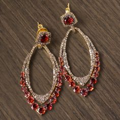 Gracefully dangling an eye catching 2 inches and fully encrusted with glittering natural diamonds and vivid red garnets, these striking drop earrings have an elegant air of old Hollywood glamour! Featuring a rich border of brightly saturated red garnets and sparkling with approximately 1.5 carats of pave set natural earth mined diamonds, these beauties could catch your eye from across the room. Rich in color and sparkling with natural diamonds and gemstones, these earrings will bring a touch of Dazzling Diamond Earrings With Pave Setting For Party, Red Diamond Party Earrings, Red Diamond Earrings For Party, Formal Red Earrings With Diamond Accents, Formal Ruby Jewelry With Pave Setting, Dazzling Party Earrings With Pave Setting, Red Diamond Drop Earrings, Red Ruby Diamond Earrings For Wedding, Red Diamond Accented Jewelry For Evening