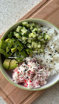 a bowl filled with rice, cucumber and other vegetables on top of a cutting board