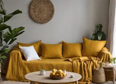 a living room with yellow linens and pillows on the couch, coffee table and potted plants