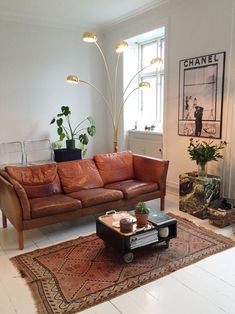 a brown leather couch sitting on top of a living room floor next to a window