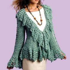 a woman wearing a green crochet jacket and white top standing in front of a purple background