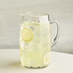 a pitcher filled with lemonade and ice on top of a white tablecloth covered table