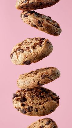 chocolate chip cookies falling in the air on top of each other, with one cookie above them