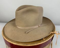 Always a classic, this 1940's "Stetson" Open Road fedora will top off any suit or western outfit! The beaver felt fedora is a pleasant warm sandy beige color - like lost in a dust storm. This hat also features a narrow ribbed tone-on-tone grosgrain silk ribbon band and matching taped edge.  It has a leather inner hat band and is unlined. By Stetson and with the original owner's name handwritten in the leather sweatband - what a fun piece of history! Includes the original box! This hat is in grea Vintage Fitted Felt Hat For Ranch, Vintage Fitted Hat Bands For Rodeo, Vintage Fitted Hat For Ranch, Fitted Vintage Hat For Ranch, Fitted Western Style Six-panel Hat Bands, Vintage Top Hat With Flat Brim For Ranch, Vintage Flat Brim Top Hat For Ranch, Vintage Fitted Fedora For Ranch, Fitted Vintage Fedora For Ranch