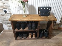 a wooden bench with several pairs of shoes on it and a vase filled with flowers