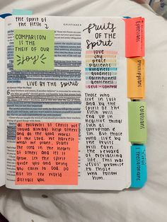 an open bible with colorful sticky notes on the pages and words written in different languages