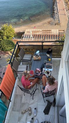 two women sitting at an outdoor table on the roof of a house near the ocean