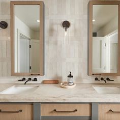 a bathroom with double sinks and two mirrors on the wall next to eachother