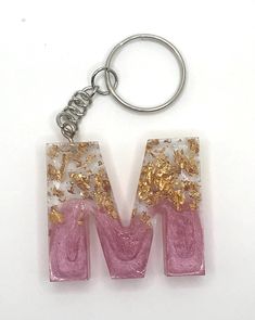 the letter m is made up of pink and gold glitters on it's sides