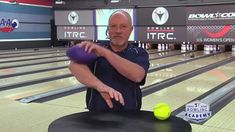 a man holding a purple ball in his right hand and bowling balls on the other