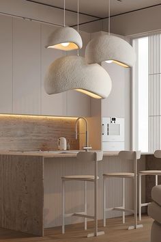 three lights hanging from the ceiling above a kitchen island with stools and countertop