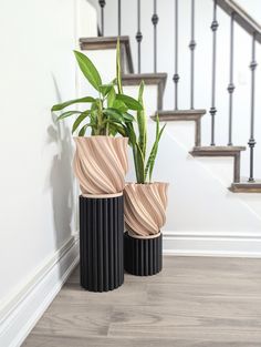 two black vases sitting next to each other on top of a hard wood floor