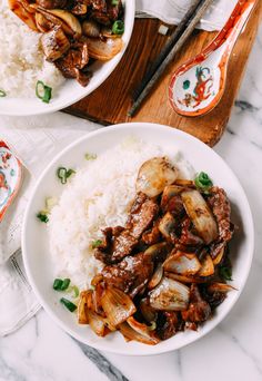 two plates filled with meat and vegetables on top of white rice next to spoons