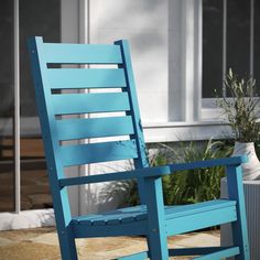 a blue rocking chair sitting on top of a stone floor next to a potted plant