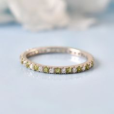 a close up view of a wedding band with green and white stones on the side