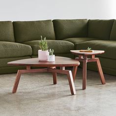 two wooden tables sitting next to each other in front of a green couch and coffee table