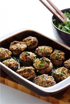 a casserole dish filled with meatballs and green beans next to a bowl of salad