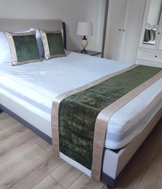 a bed with white sheets and green pillows