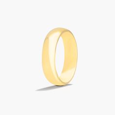 a plain yellow gold wedding ring on a white background with the light shining through it