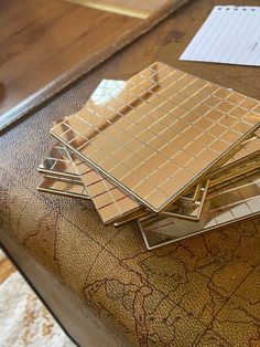 a stack of tiles sitting on top of a table next to a pen and paper