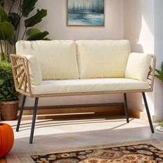 a white couch sitting on top of a wooden floor next to a potted plant