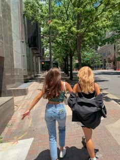 two women walking down the street with their hands in each other's back pockets